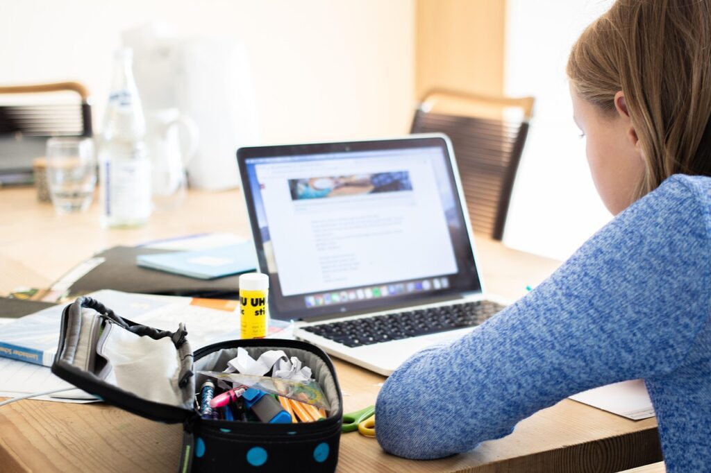 Student researching online with a laptop, open browser tabs, and notes on the desk.