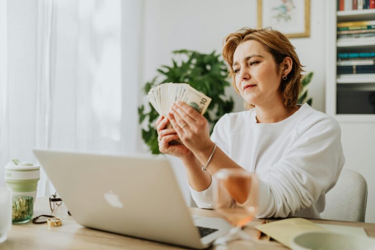Girl holding cash while sitting with a laptop, symbolizing hidden ways to earn money online in 2025